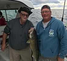 captain Joe Mellish holding a big fish with an older gentleman on the lake